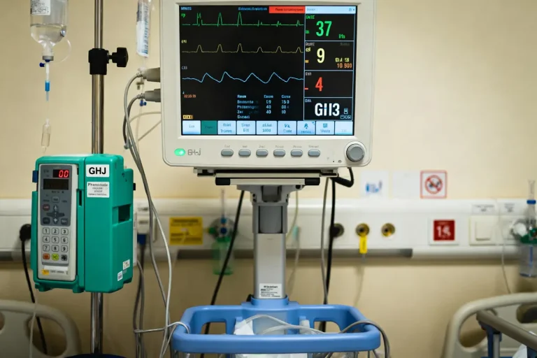Moniteur médical et perfusion dans une chambre d'hôpital avec affichage des signes vitaux.