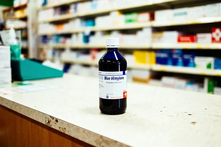 Bouteille de sirop médicinal Blue DEmylane sur comptoir de pharmacie flou en arrière-plan.